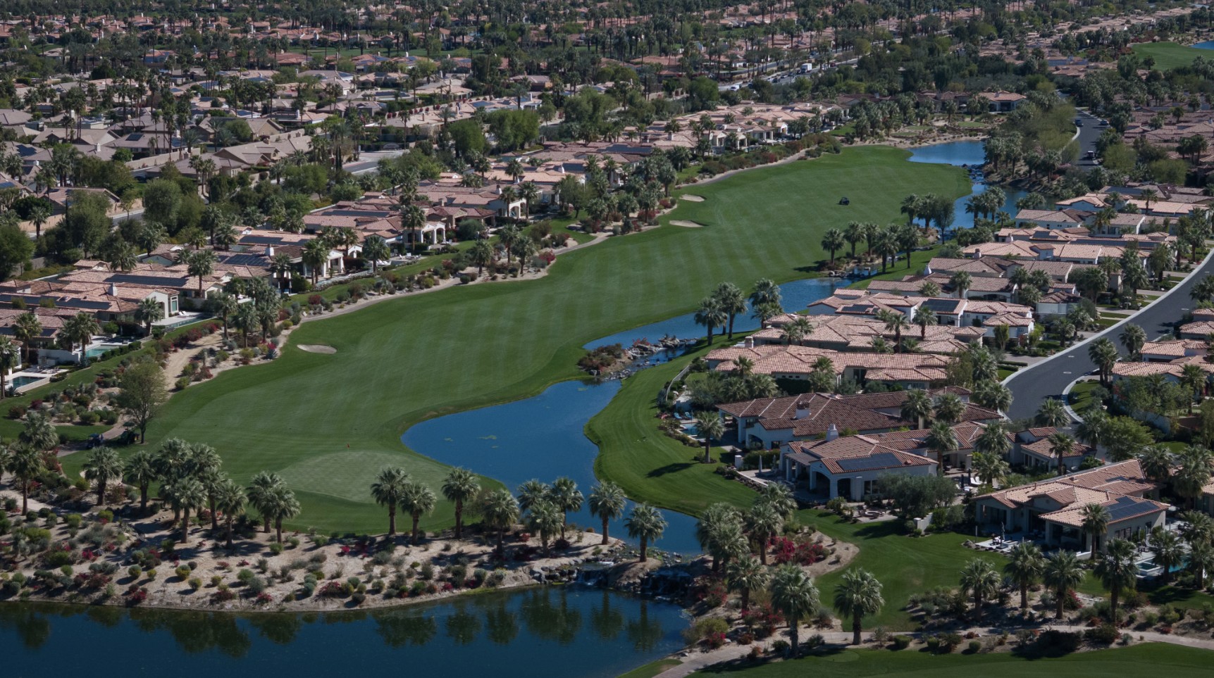 Aerial view of a fairway and lake at Toscana Country Club with homes on both sides