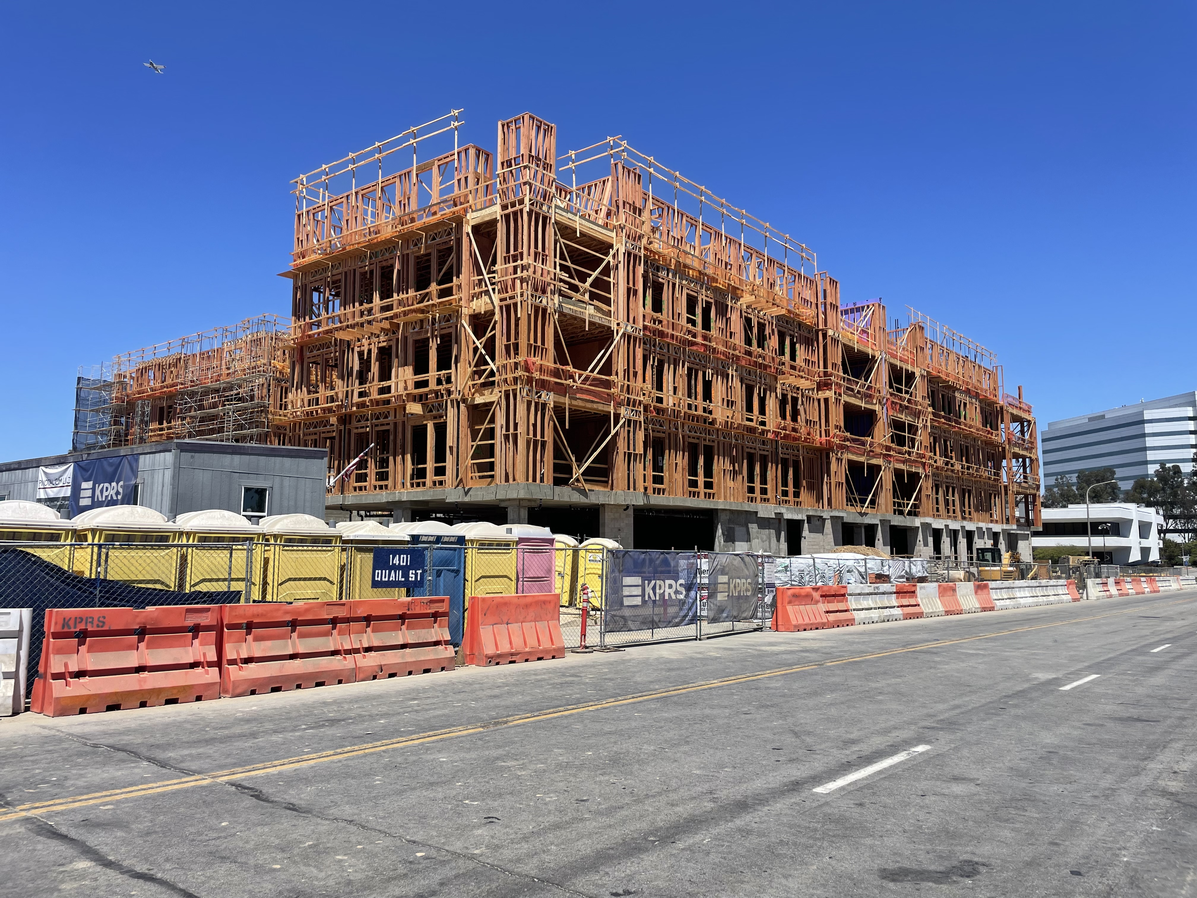 1401 Quail Street Newport Beach under construction by KPRS with framing visible and a plane overhead near John Wayne Airport