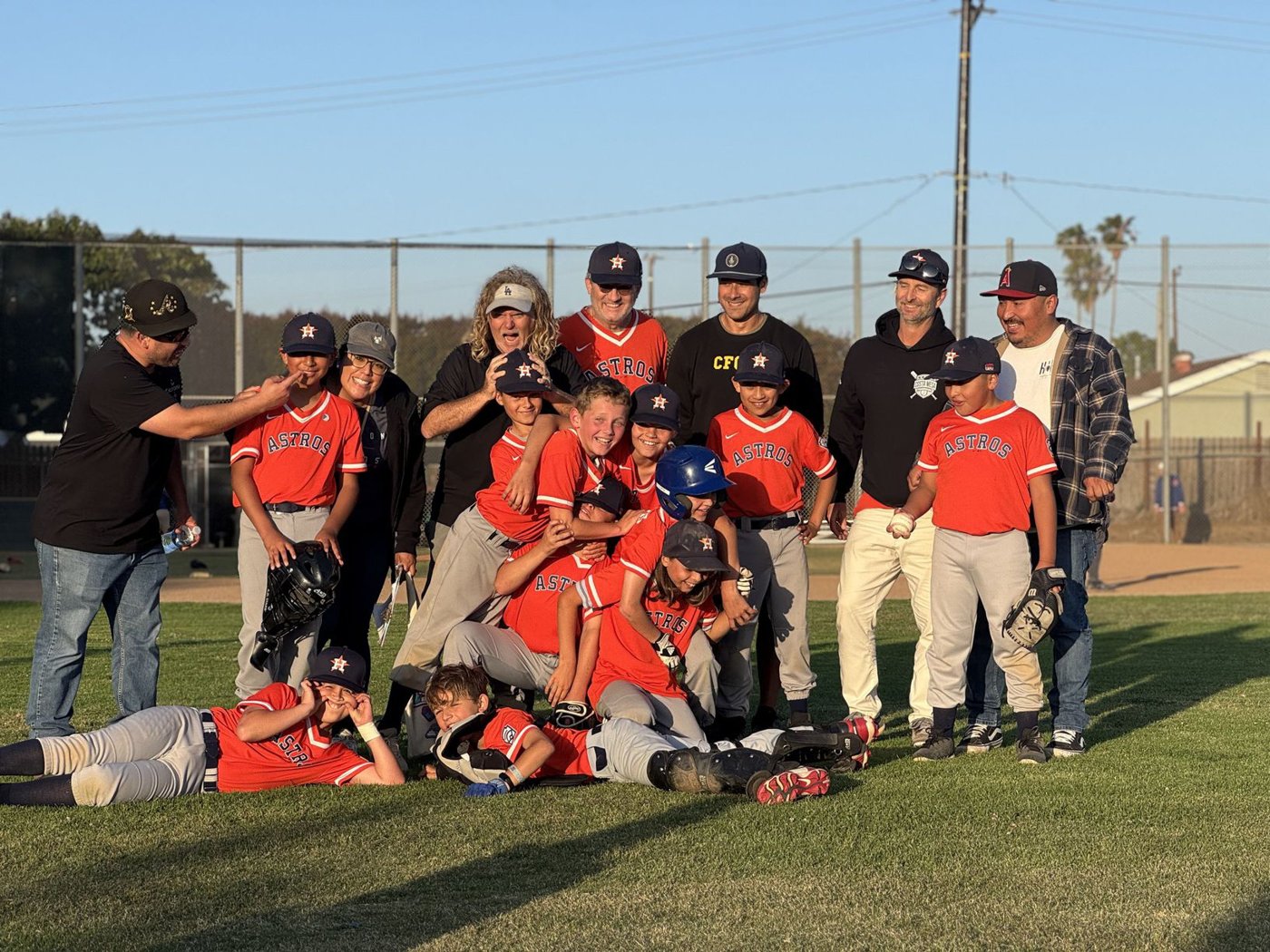 Costa Mesa Little League baseball team and coaches celebrating on the field after a game
