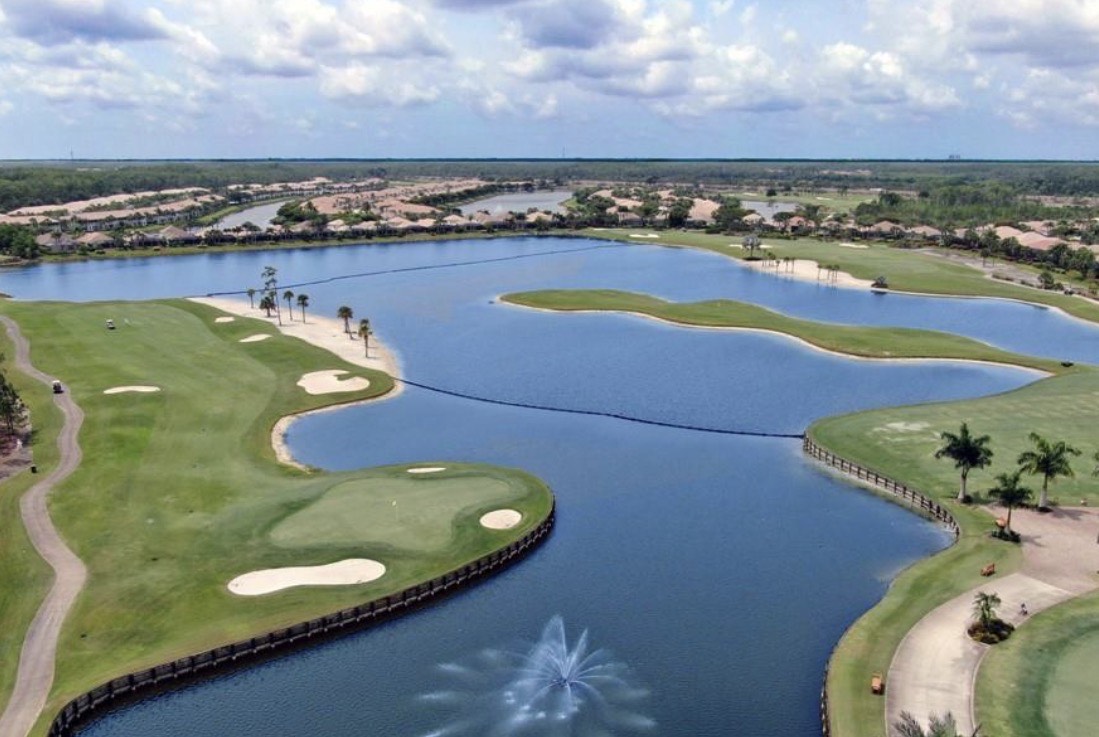 The image depicts a modern clubhouse exterior featuring Spanish-style architecture, set within a prestigious gated community in Fort Myers. Surrounded by lush landscaping, the clubhouse serves as a central hub for residents, offering community amenities and a tranquil setting for relaxation.