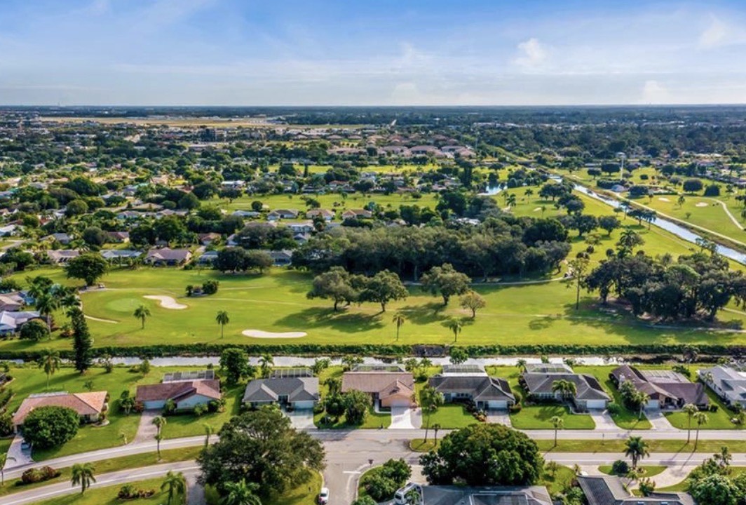 The image showcases a modern condo interior with sleek granite countertops and an open floor plan, allowing for an abundance of natural light to flood in through large windows. This fantastic condo, ideally situated in Fort Myers, features a spacious living area that flows seamlessly into the formal dining room.