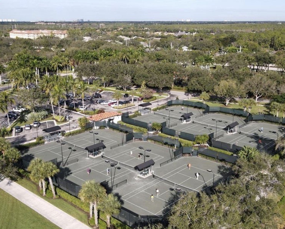 The image depicts the picturesque tree-lined streets of Village Walk, showcasing beautifully maintained homes surrounded by mature landscaping. This tranquil community in Naples offers a comfortable living space with access to resort-style amenities and is ideal for prospective property consumers looking for homes for sale.