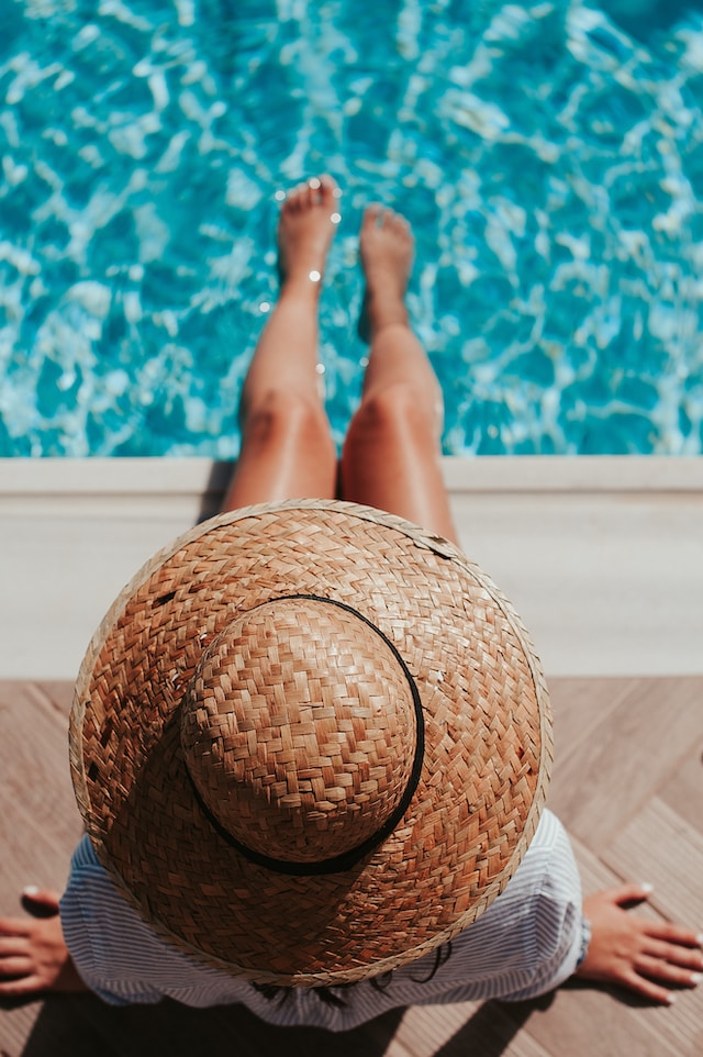A top view of a woman in a straw hat swimming at a house with a pool for sale in Utah 