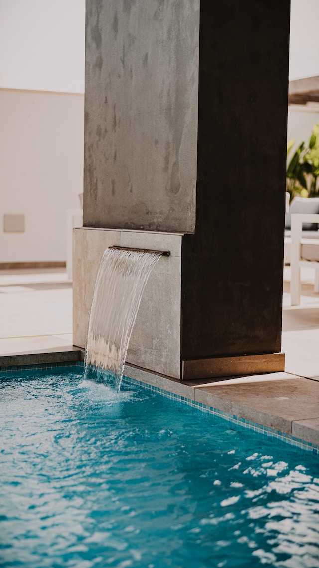 A small waterfall coming out of a column into a swimming pool