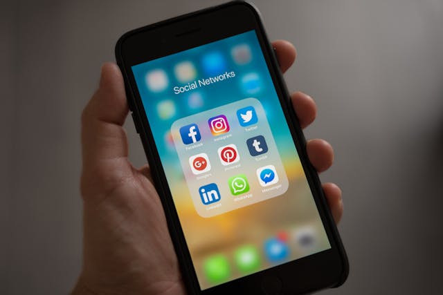 A person holding their iPhone with social media icons
