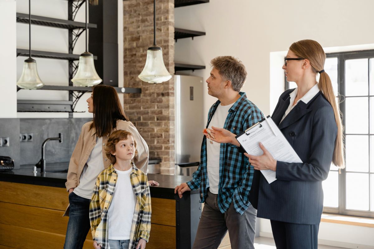 A family with a real estate agent tours a modern kitchen
