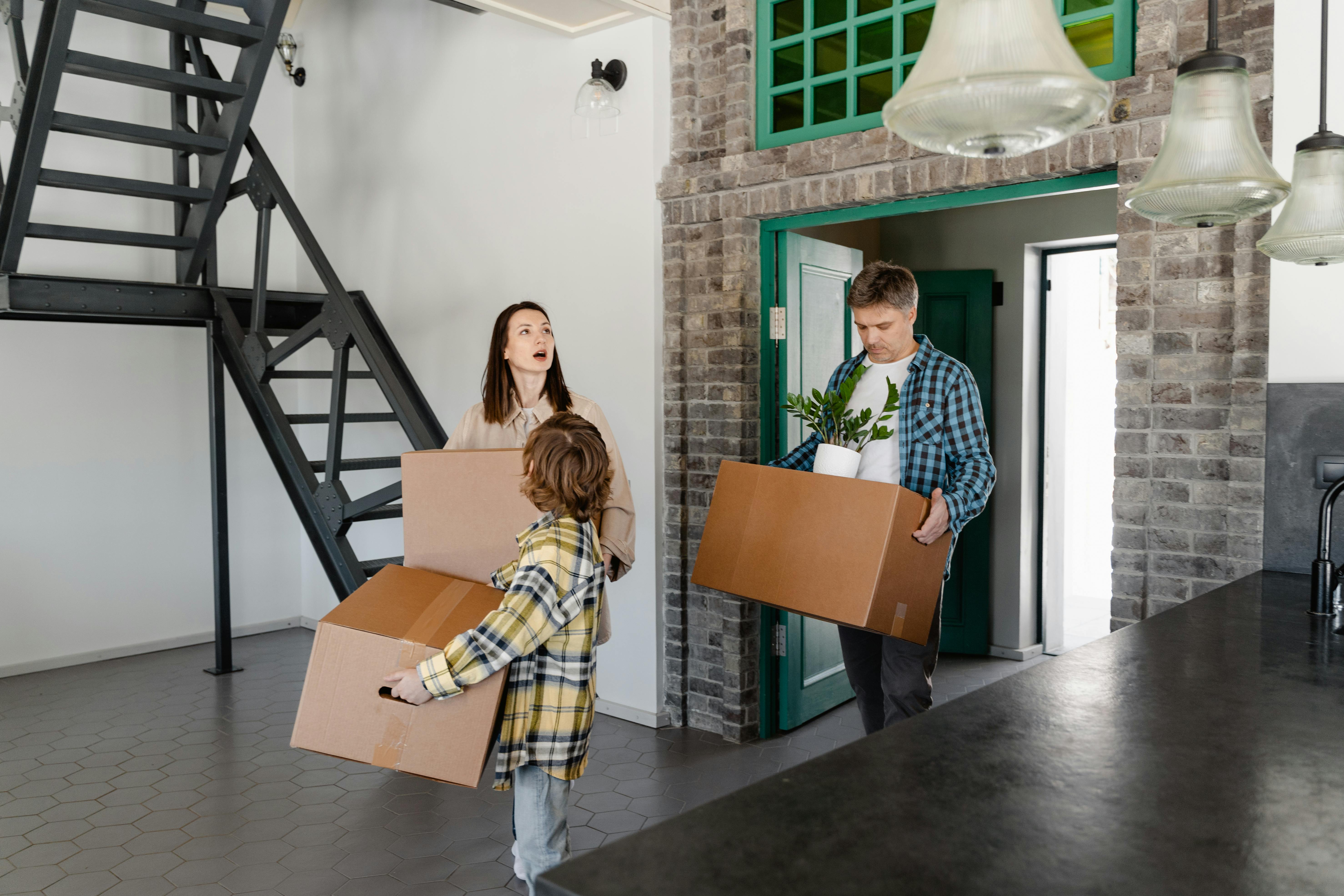 Family carrying cardboard boxes into their new house