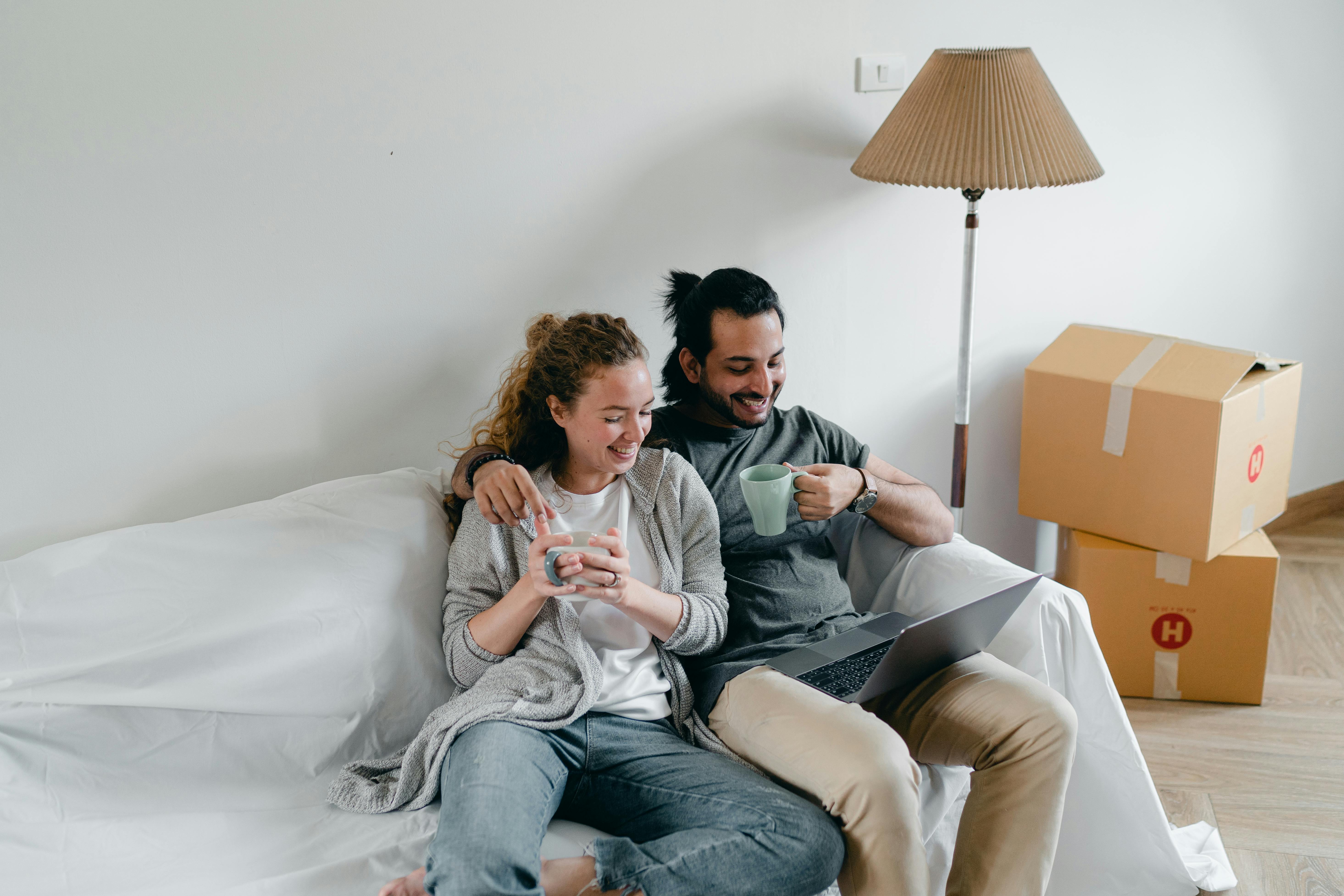Happy couple on couch with laptop in new home