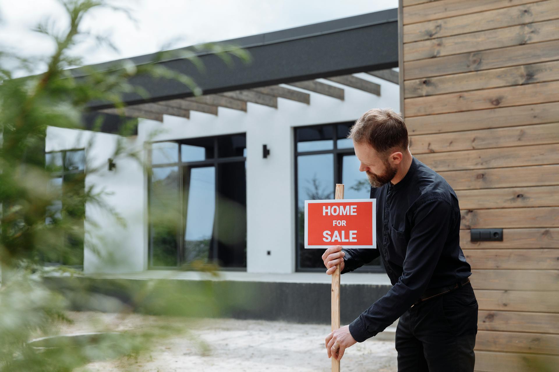 a realtor putting a home for sale sign