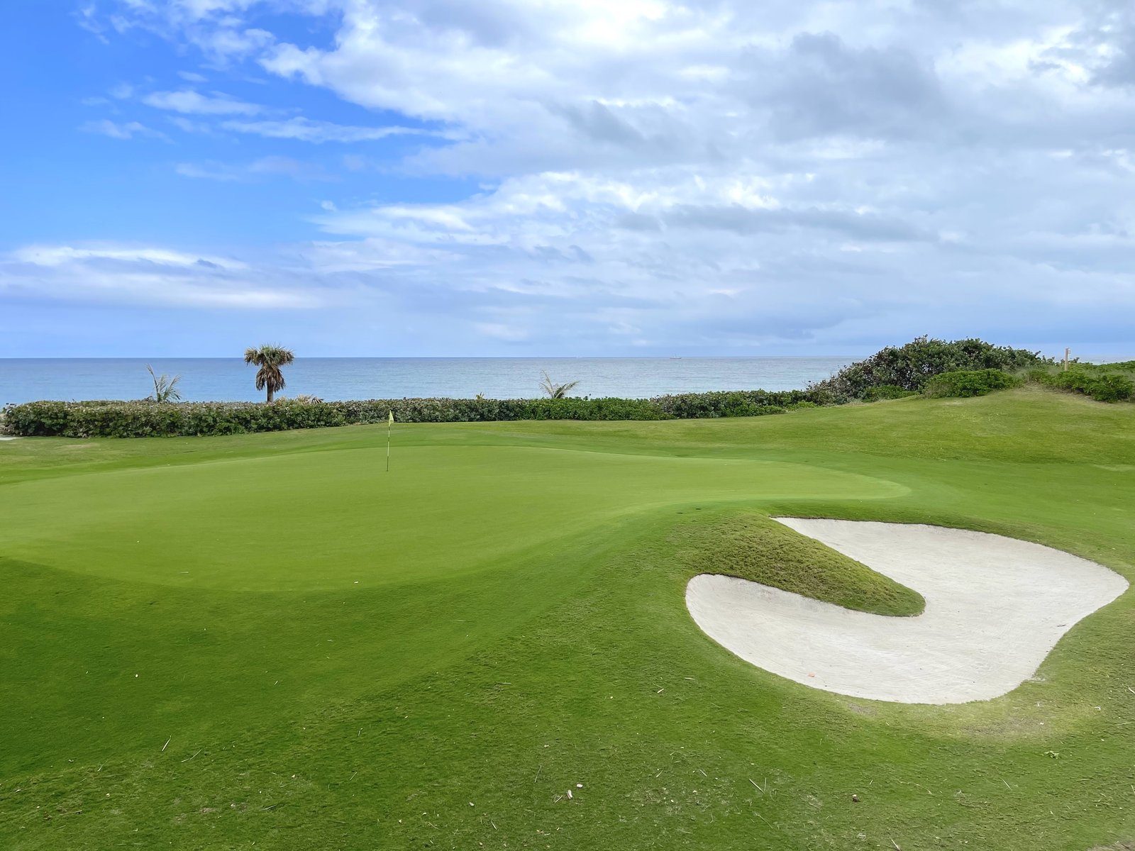 A golf green and bunker beside the ocean