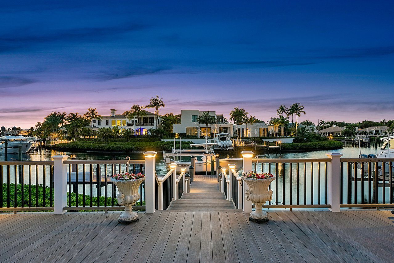 A lit dock behind a waterfront home at dusk