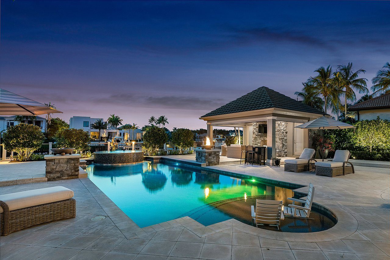 A backyard pool and pavilion at dusk
