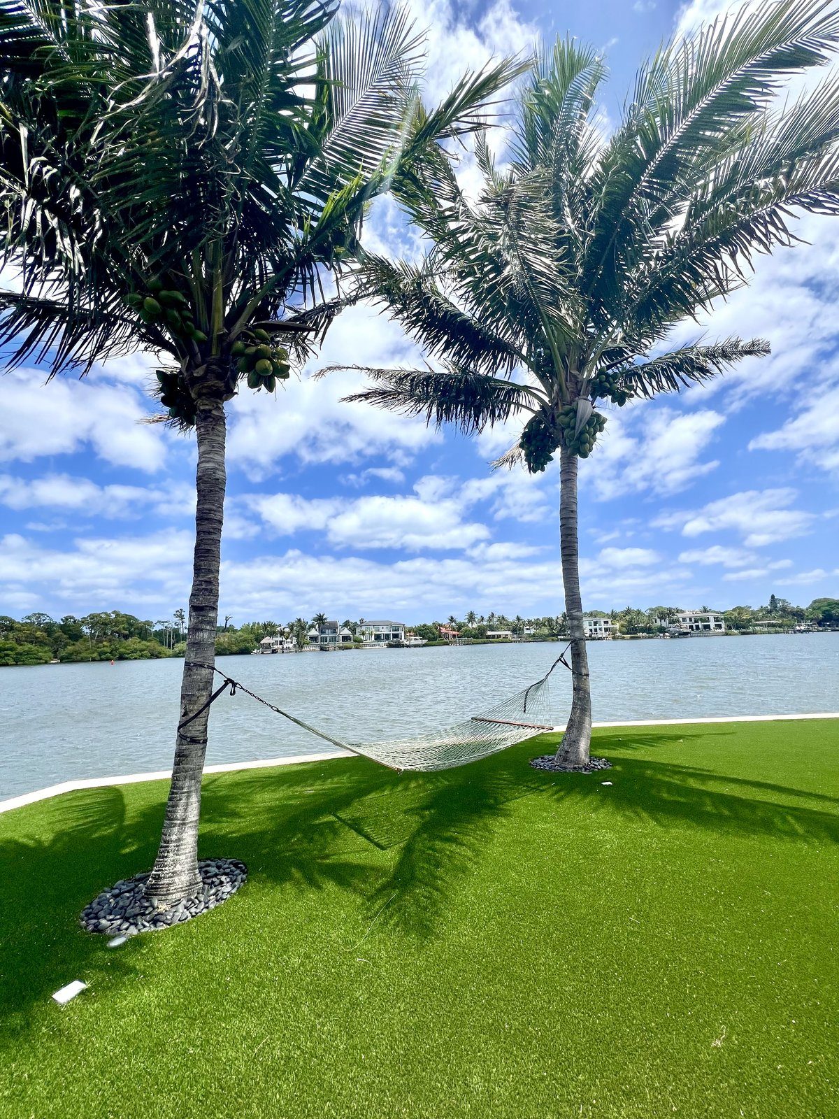 A hammock between palm trees beside the river in Tequesta