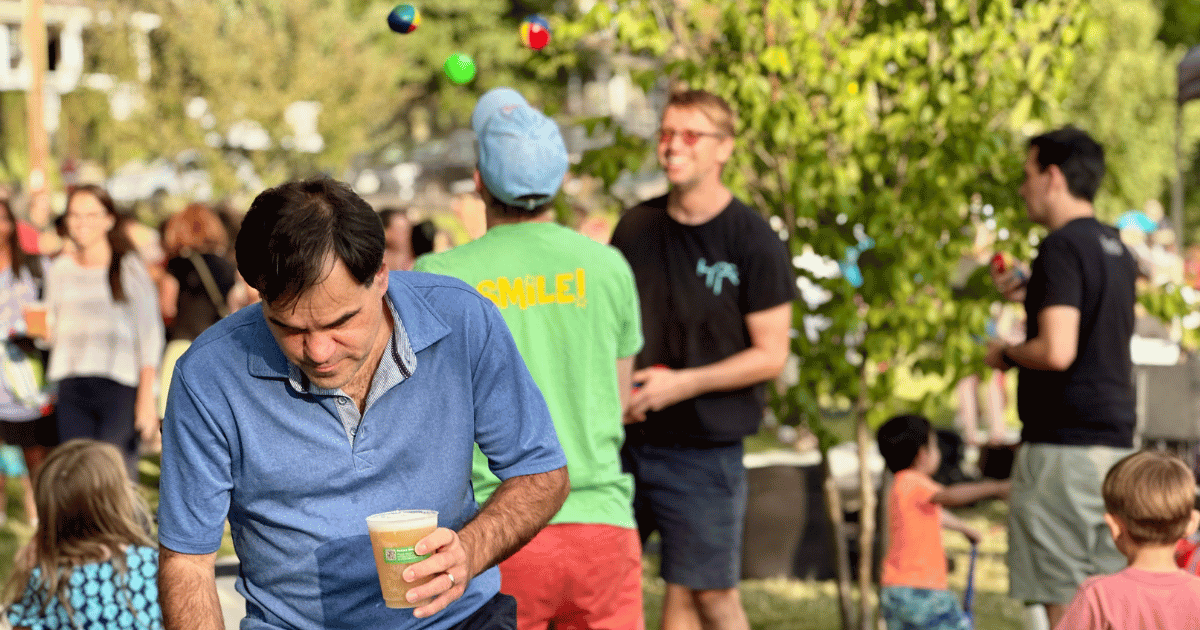 Patron happily holding a beer. Happy people behind him enjoying the festivities. 