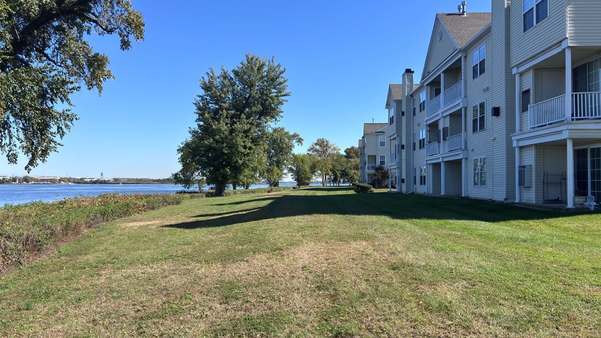 Riverfront townhomes with balconies and a lawn running down to the Delaware River