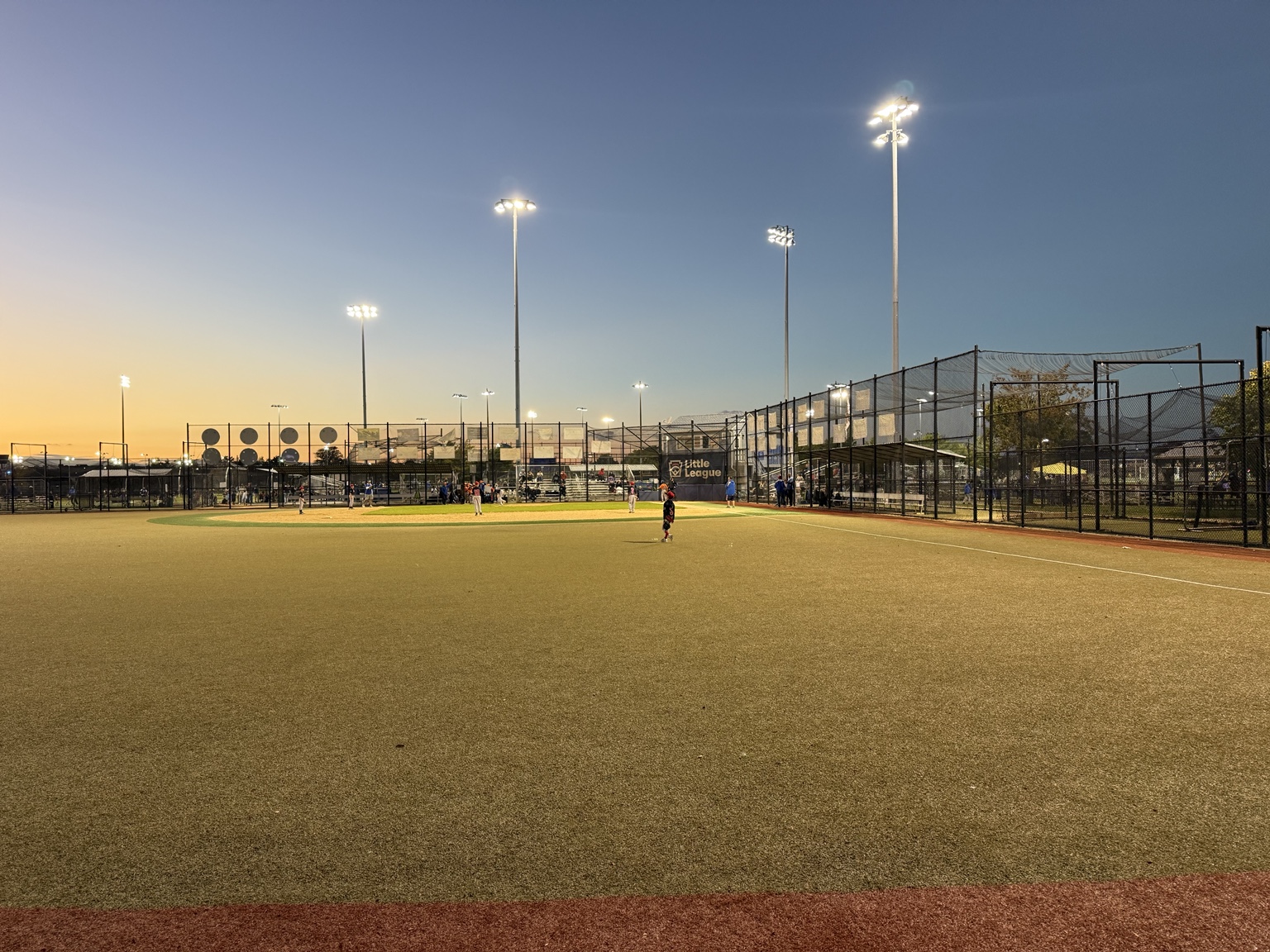 Youth baseball game on illuminated fields at John J Burns Park in Massapequa during an October evening