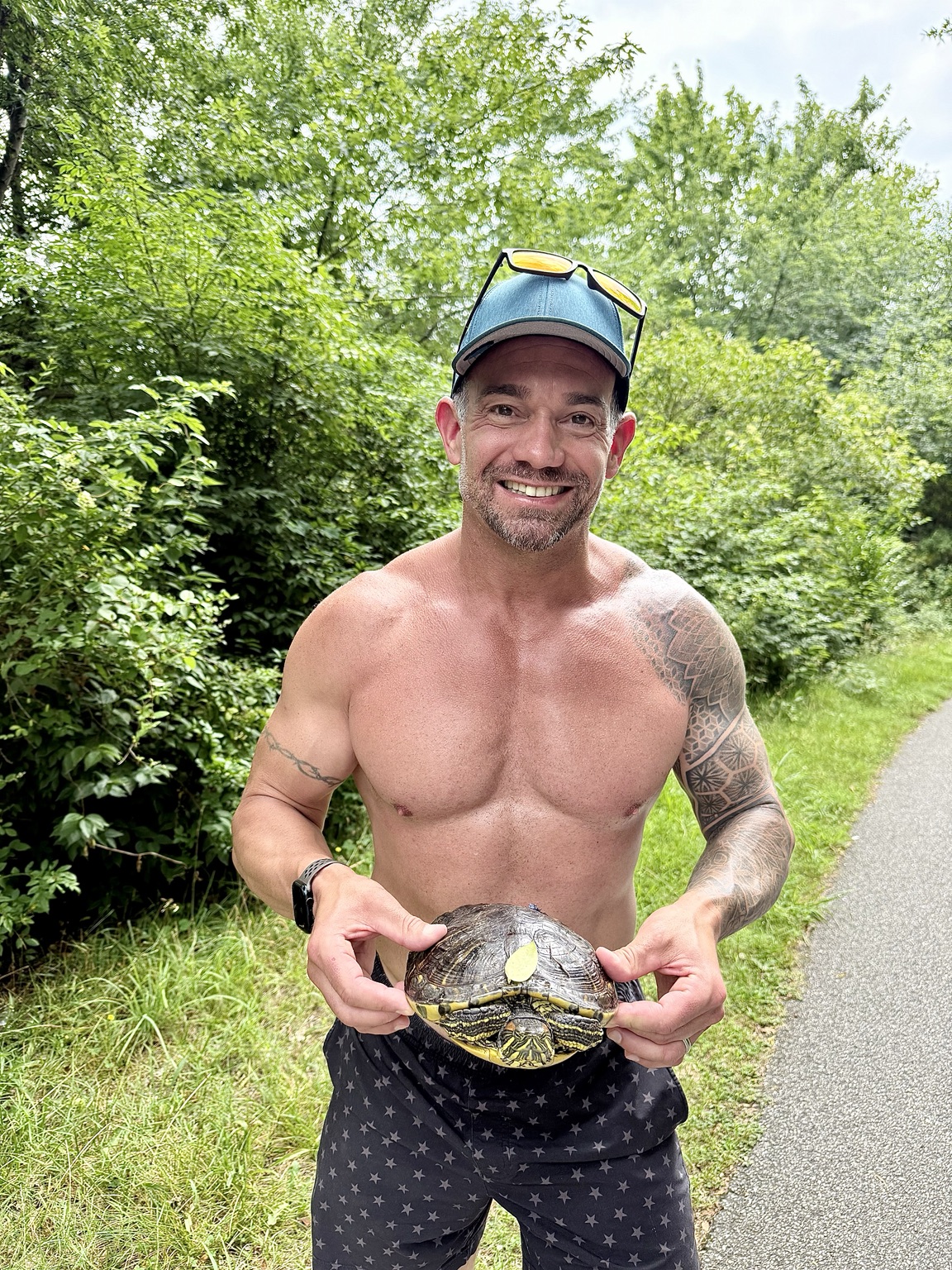 John Cordeira holding a turtle beside a paved trail during a run at Massapequa Preserve on Long Island