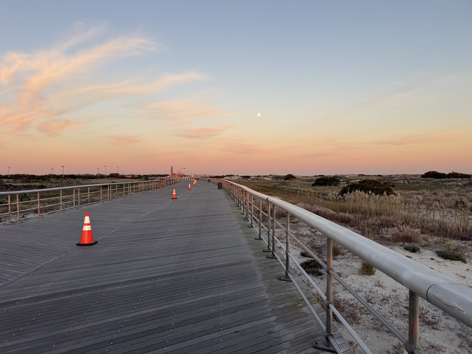 The moon above a pink evening sky, dunes and the Jones Beach boardwalk