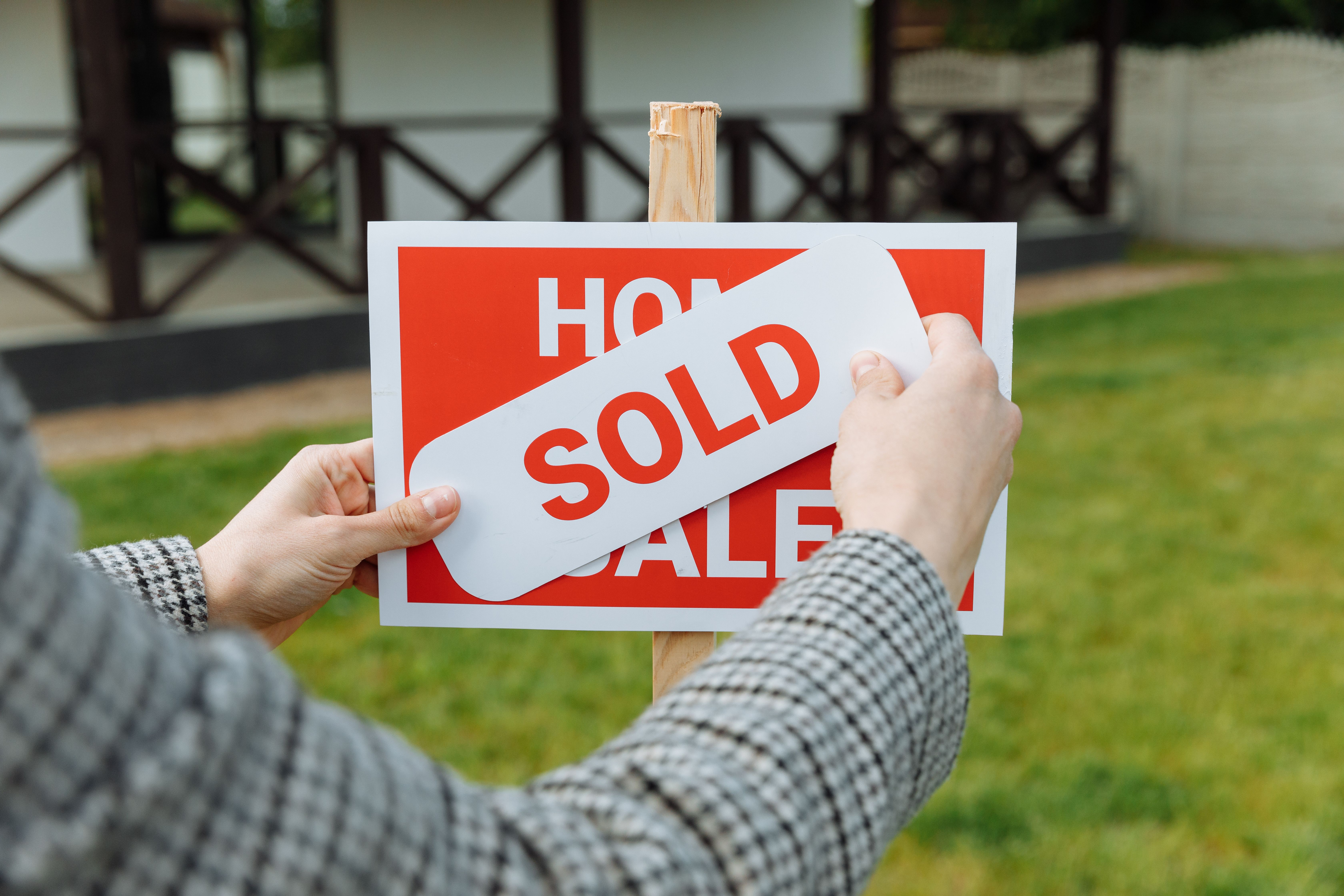 a realtor posting a sold sticker on a sign post
