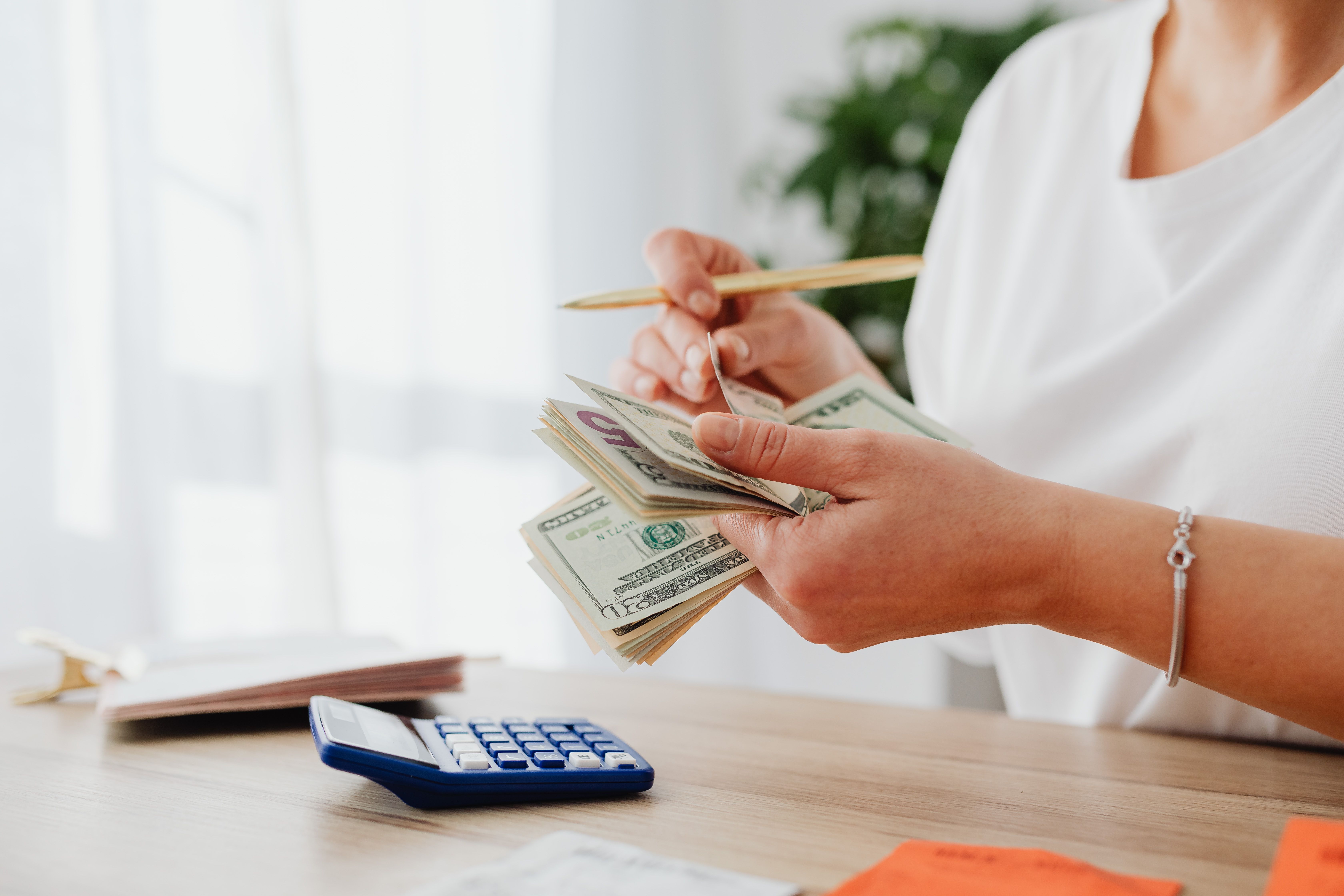 a woman counting money with calculator