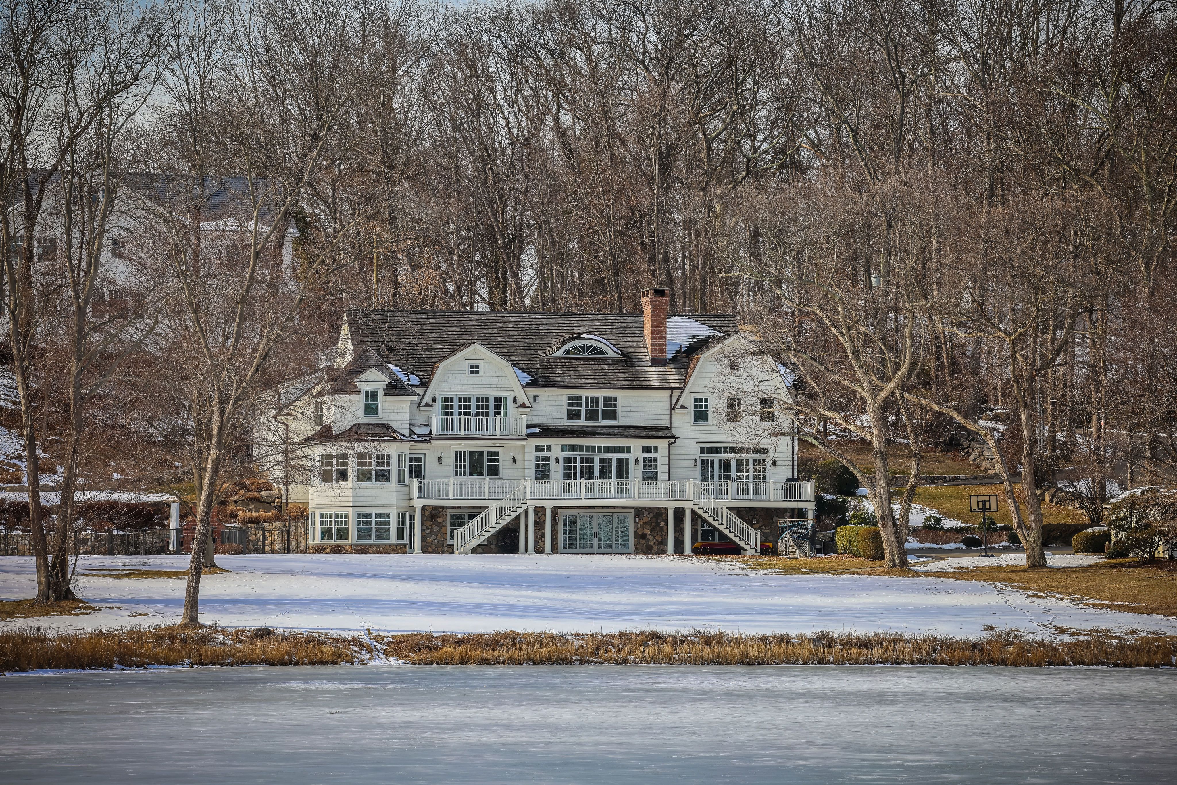 a waterfront estate surrounded by trees and snow during winter