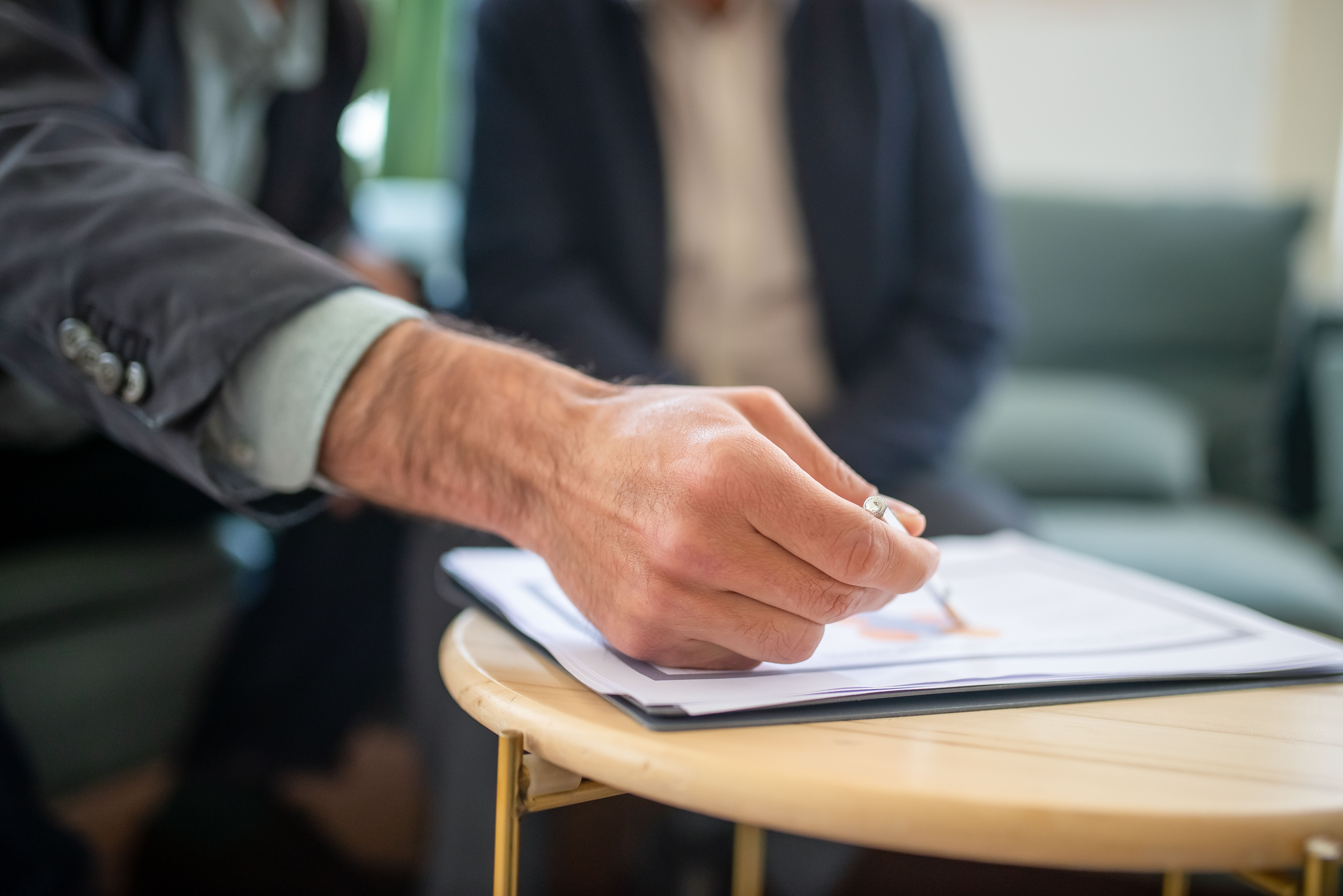man in black suit jacket writing on white paper