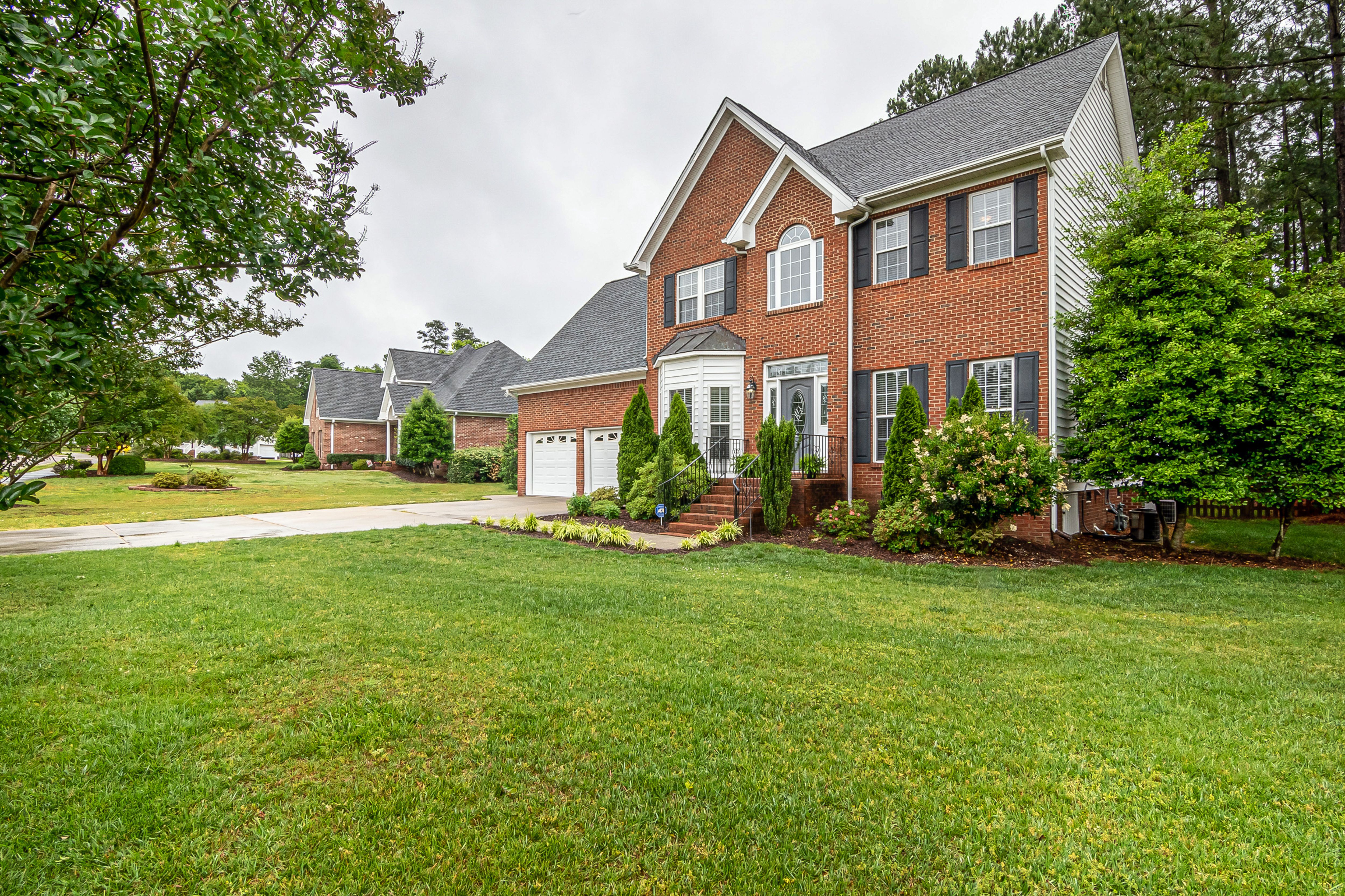 a two story brick house with attached garage and a well maintained lawn