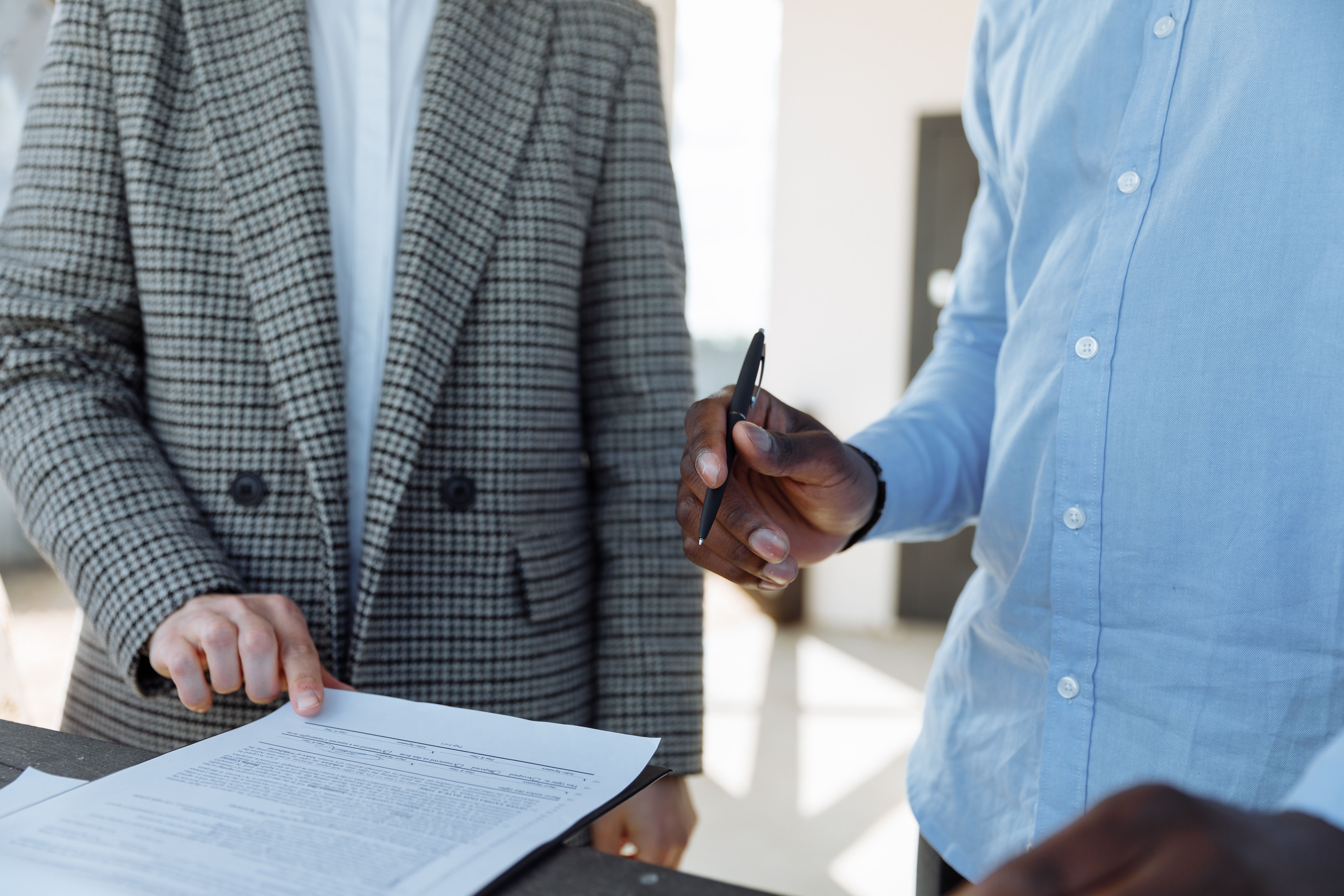 two person standing while holding a pen and paper