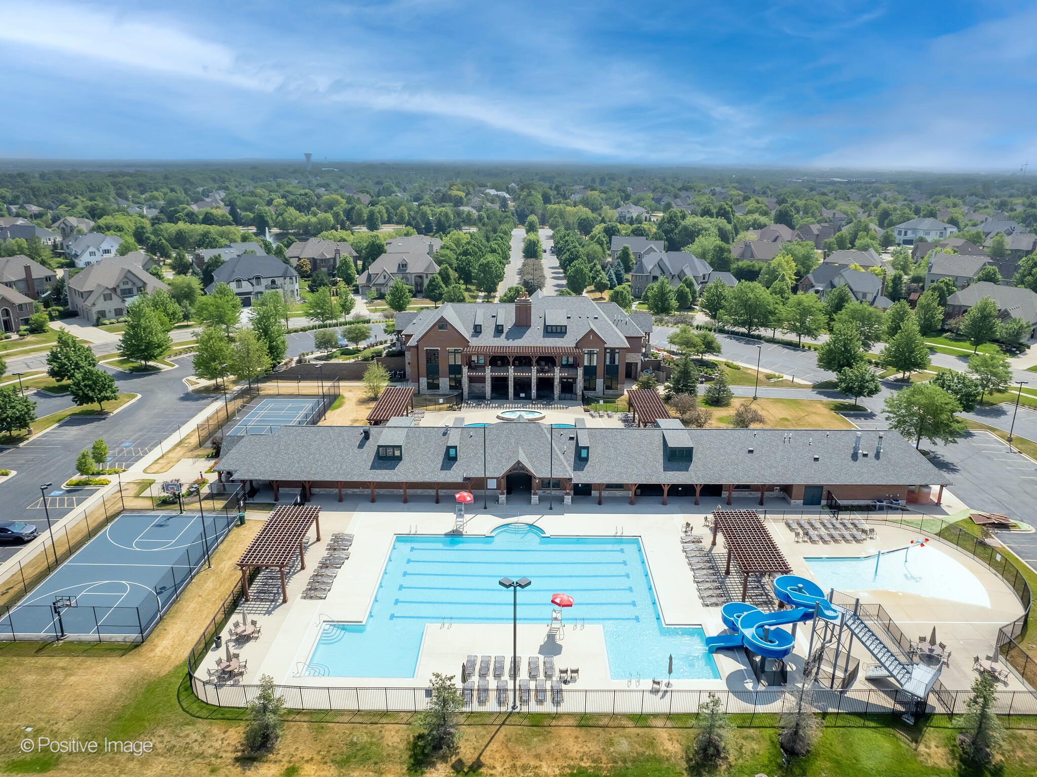 Back view of the Ashwood Park Club with outdoor swimming pools, a water slide, and basketball and volleyball courts