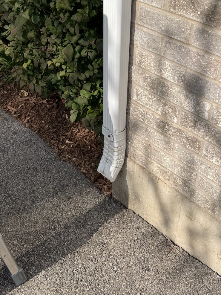 Downspout emptying right at the foundation with no extension to carry water away.