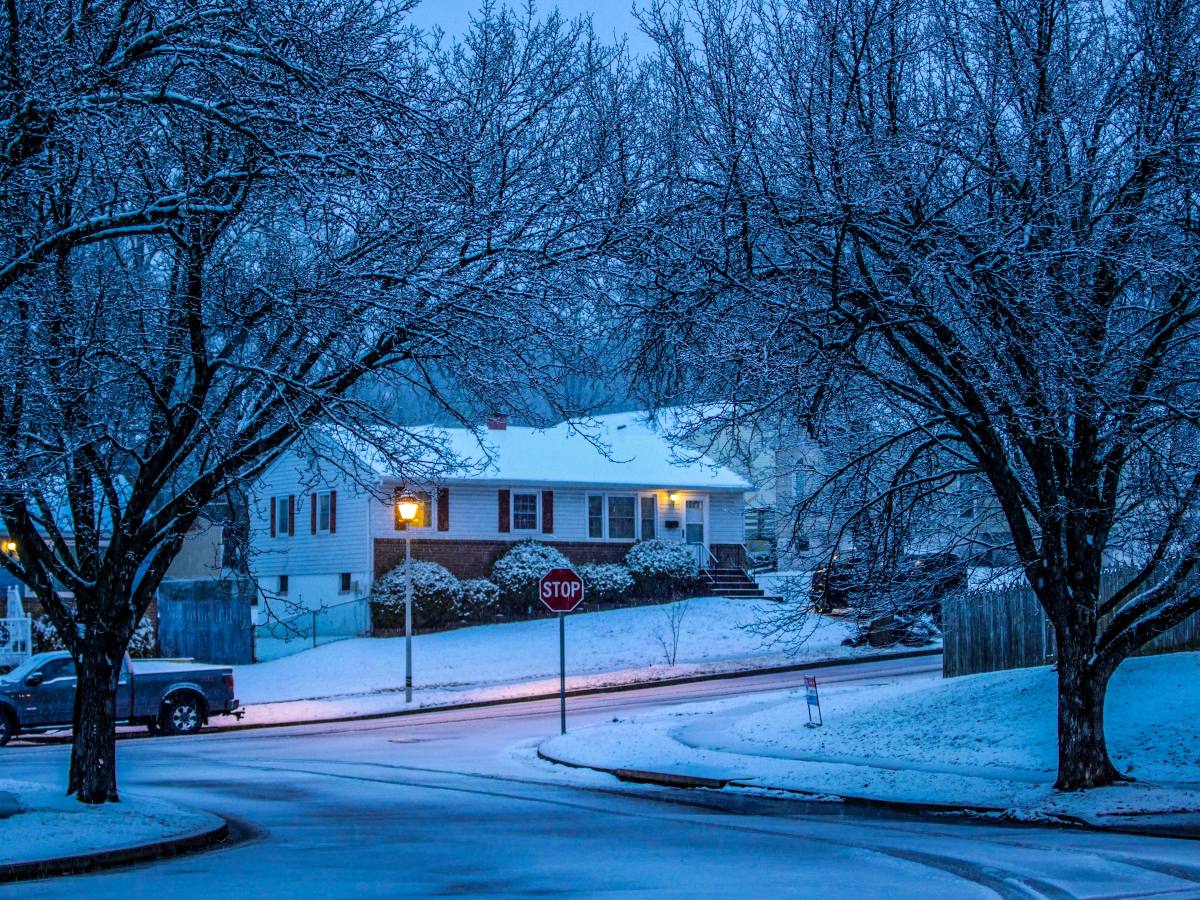 Snow-covered house and residential street in winter