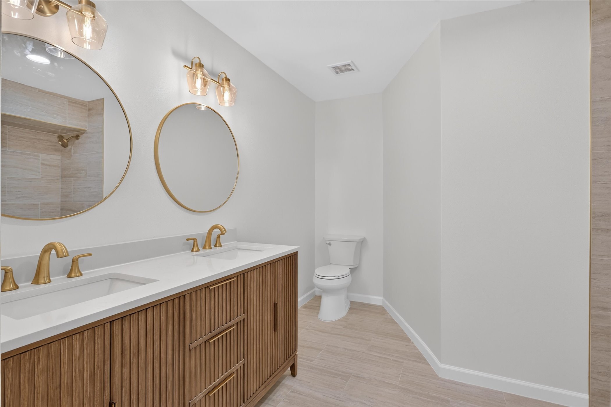 Renovated bathroom with dual vanity and gold fixtures at 6020 E University Blvd Unit 117 Dallas