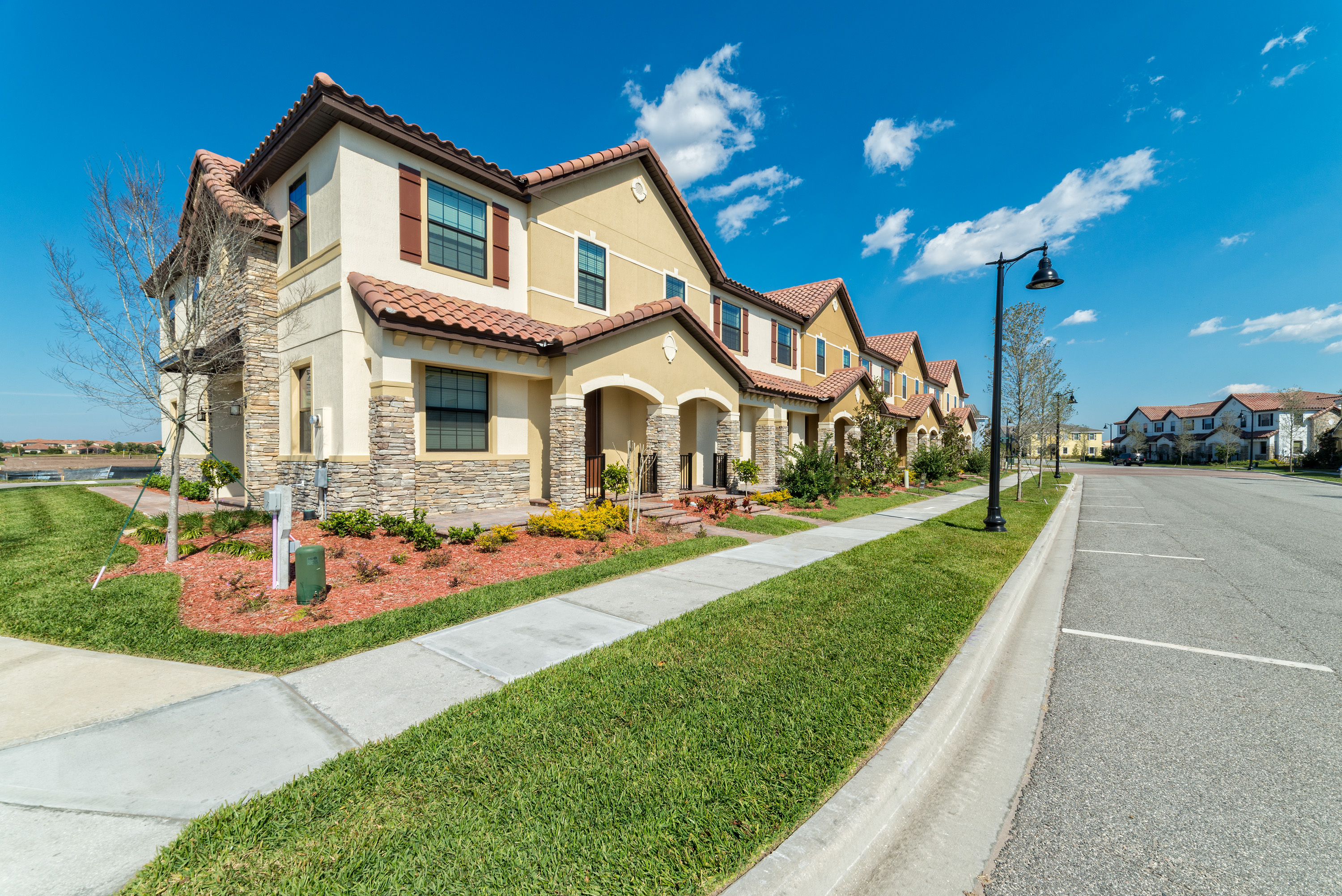 Row of modern townhomes with manicured landscaping in a gated Lake Nona community