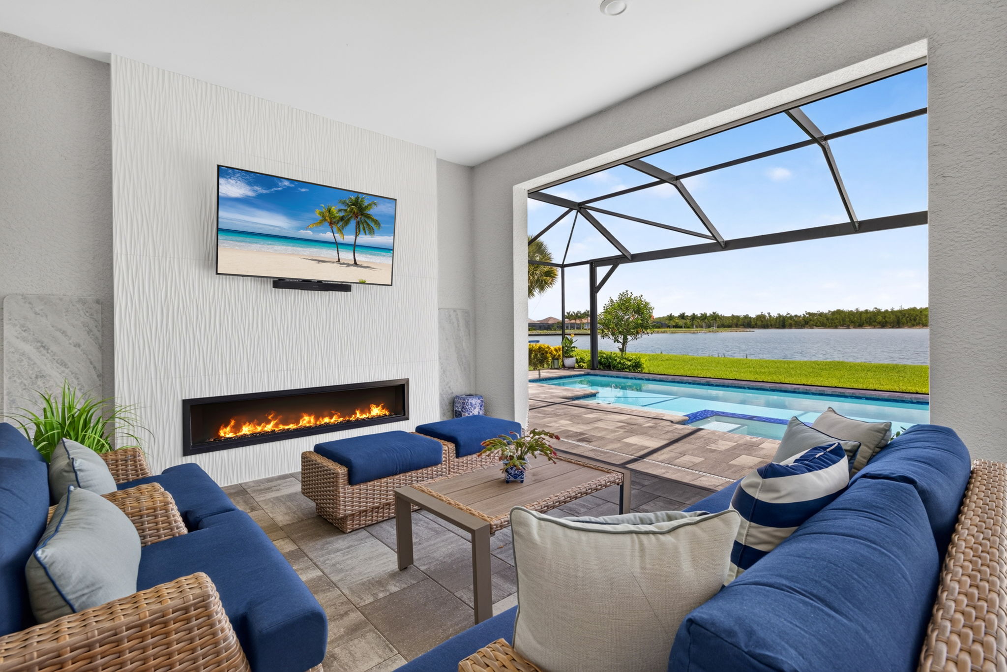 Outdoor living room with a linear fireplace and television overlooking the pool and lake