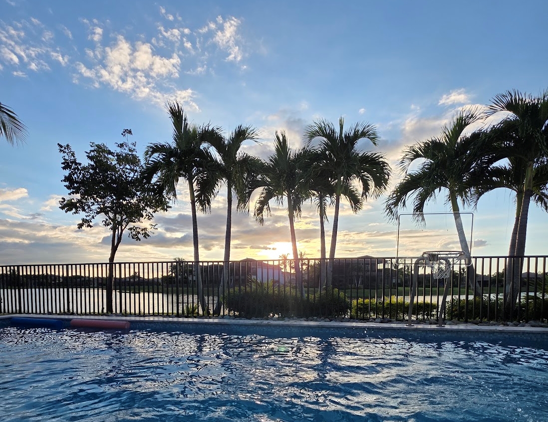 Sunset over a pool home lanai in Riverstone, a gated community in North Naples Florida
