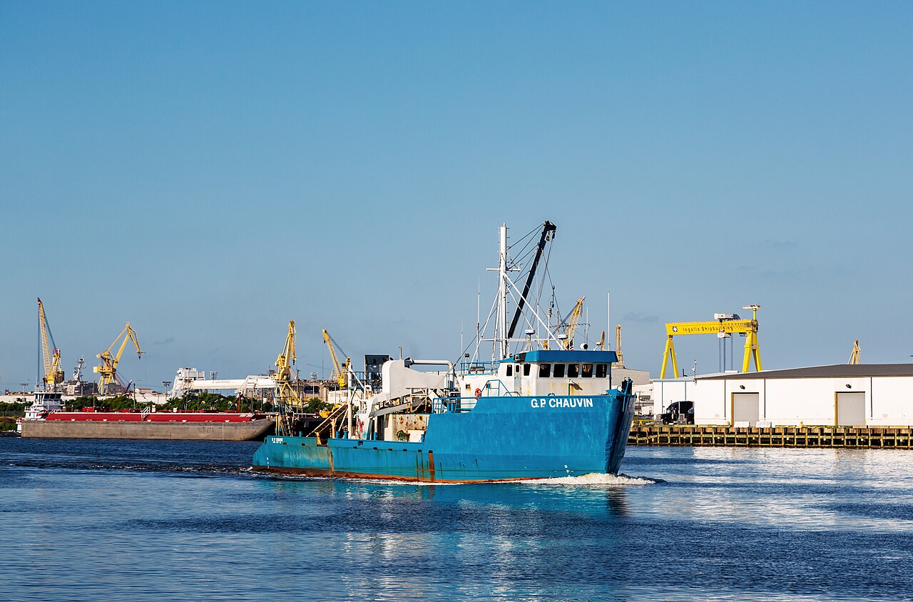 A work boat on the Pascagoula River with shipyard cranes in the background