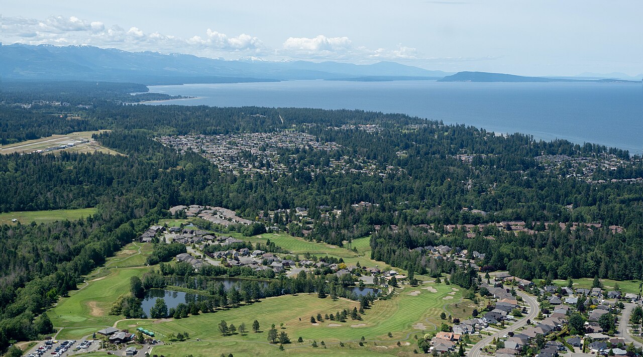 Aerial view of French Creek homes, a golf course and the Salish Sea near Parksville