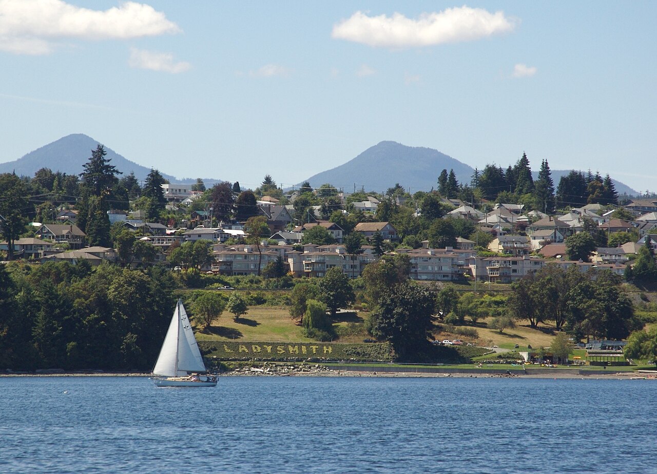Ladysmith homes on the hillside above the harbour with a sailboat in front
