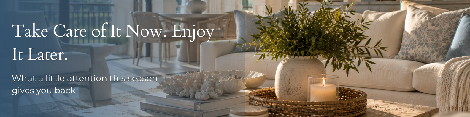 Bright, airy villa living room with a linen sofa, patterned throw pillows, and a coffee table styled with coral, a lit candle, and fresh greenery in a ceramic vase