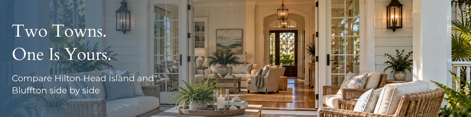 Bright coastal home interior seen through open French doors from a covered porch, with wicker seating in the foreground, a living room with neutral furnishings beyond, and a view through the front entry to the trees outside