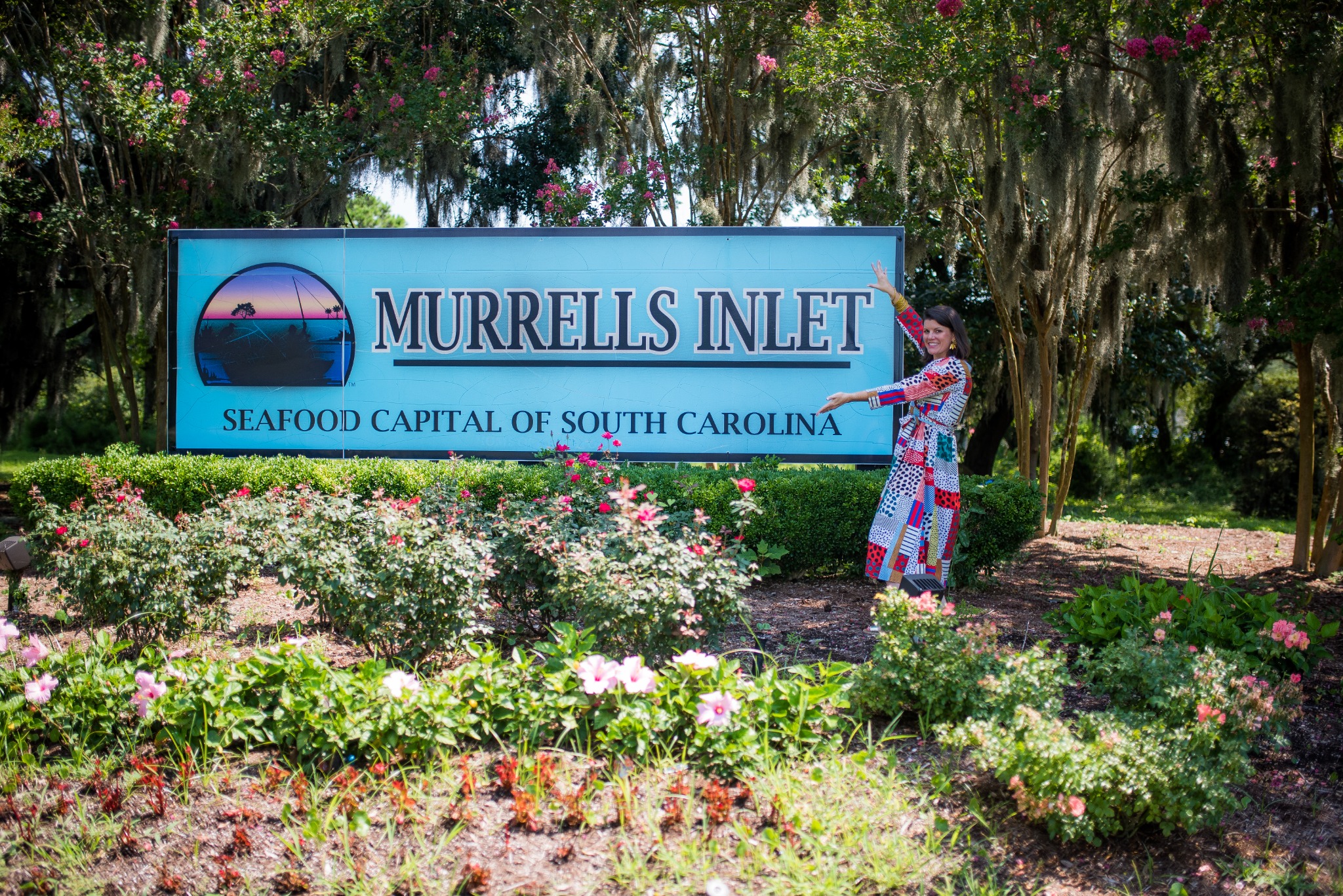 Merrill Bryan, local Realtor, beside the Murrells Inlet South Carolina welcome sign