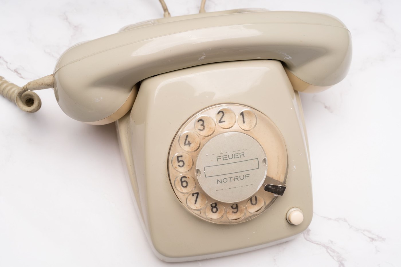 A vintage rotary telephone on a light marble surface