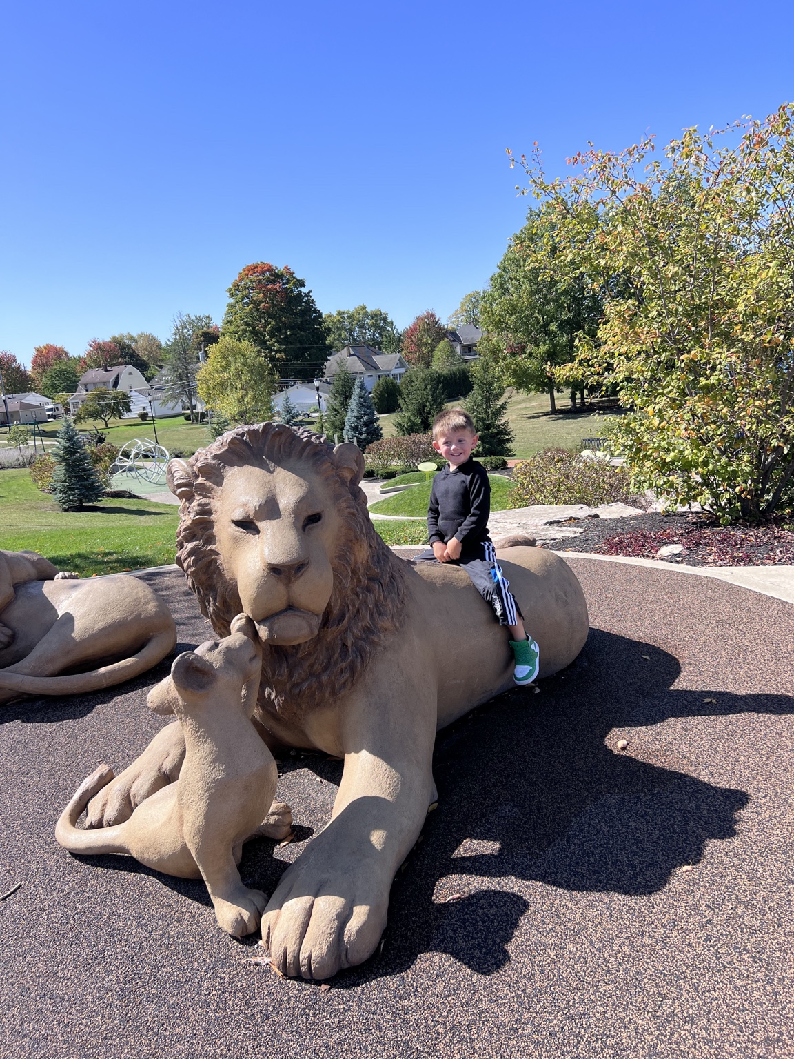 Child sitting on a large lion sculpture at a New Bremen park