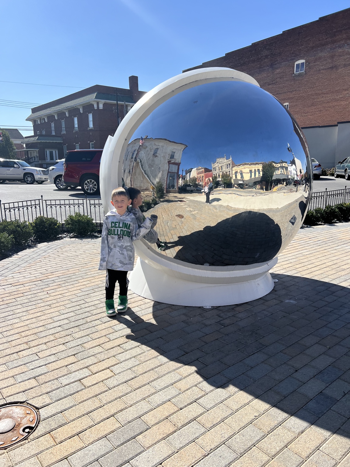 Child beside the large reflective astronaut helmet sculpture in downtown Wapakoneta Ohio