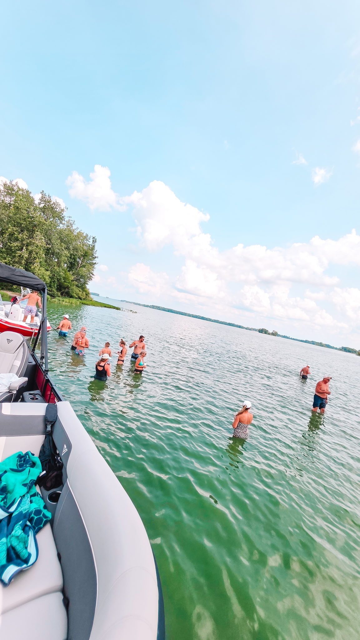 Boaters Beach on Grand Lake St. Marys with people gathering in shallow water beside boats