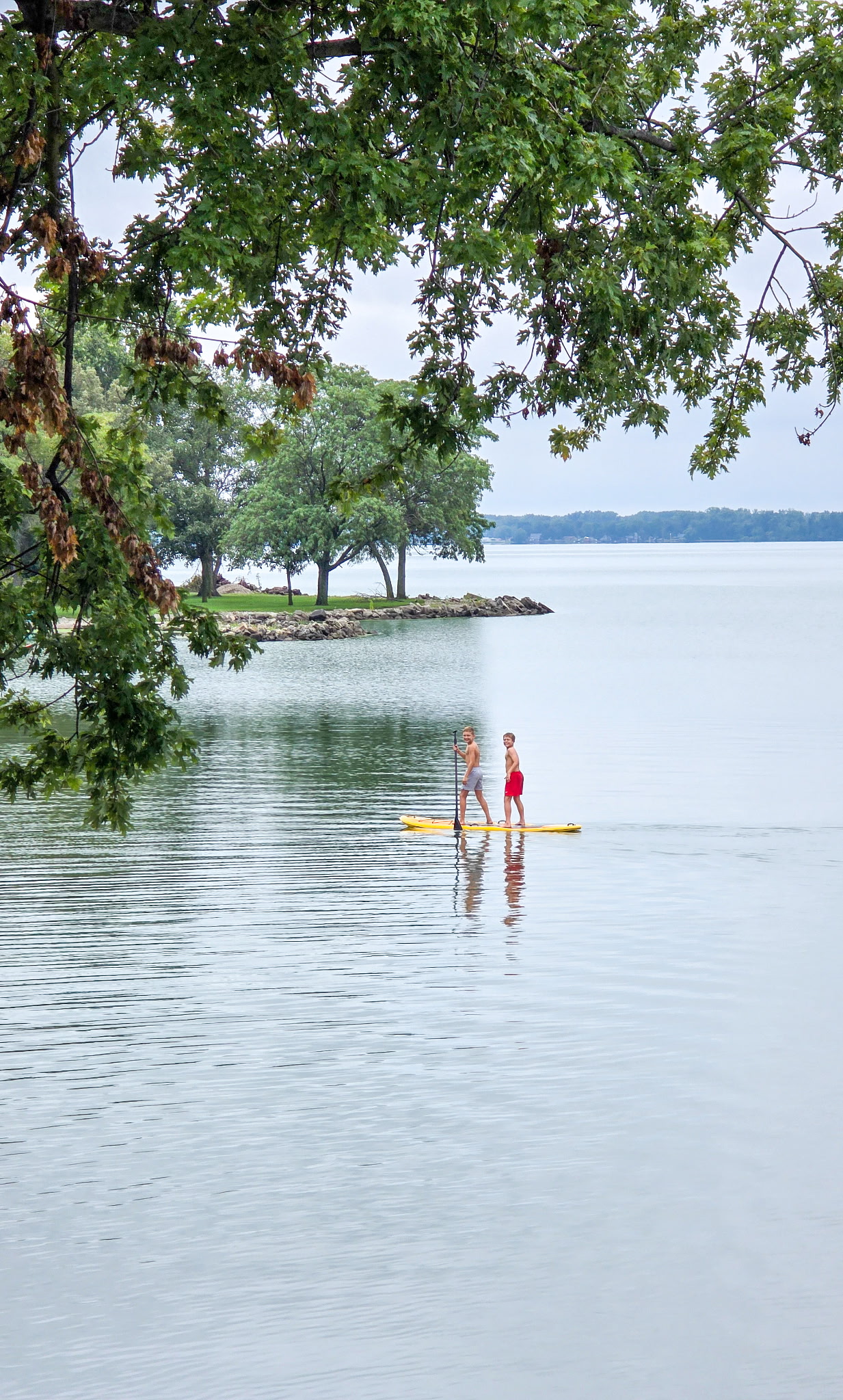 Two people standing on a paddleboard on Grand Lake St. Marys