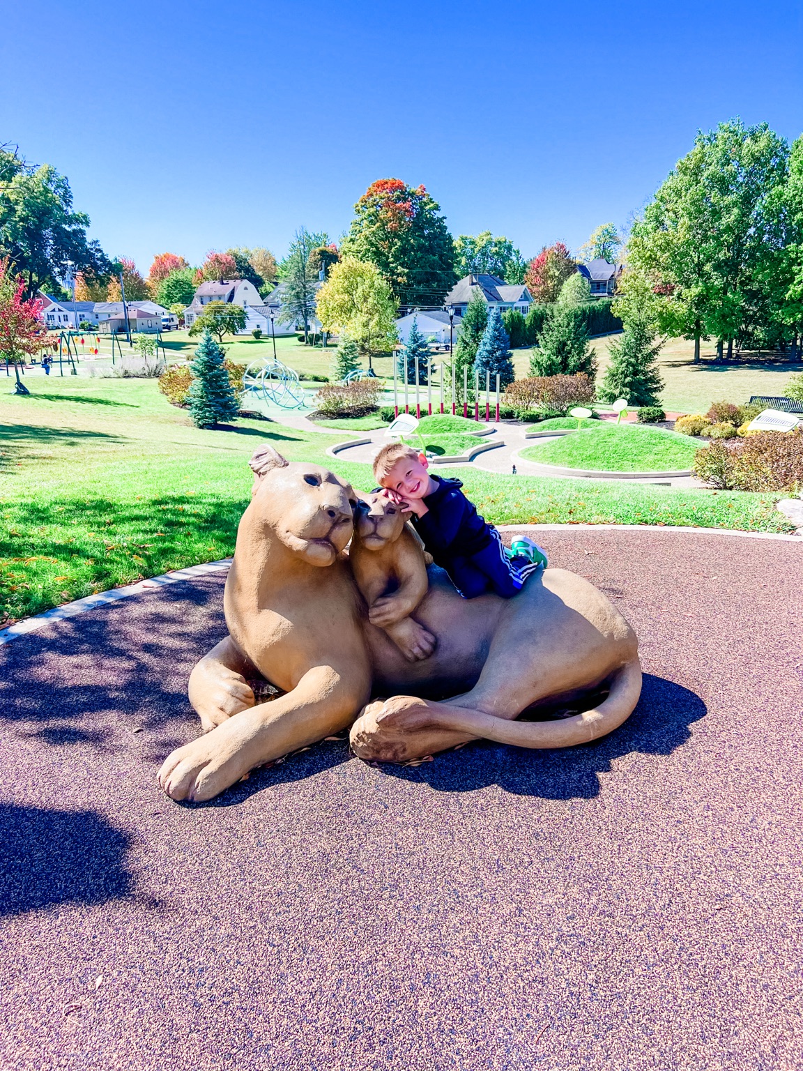 Child enjoying lion sculptures with landscaped play areas at Komminsk Legacy Park in New Bremen Ohio