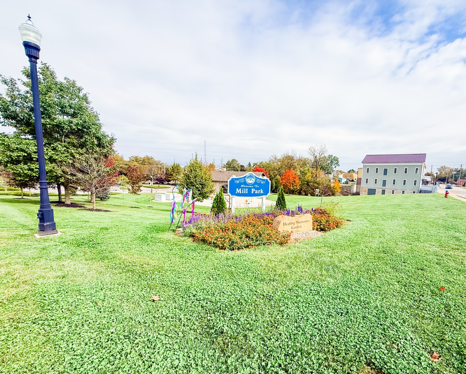 Welcome to Mill Park sign and Healing Memories Garden flower bed in St. Marys