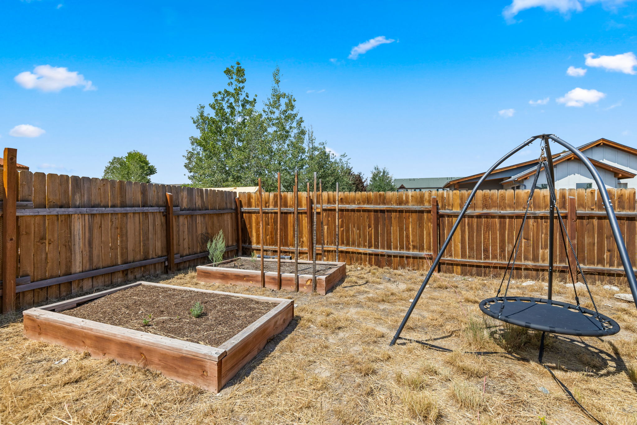 Raised garden beds and play space in the fenced yard, Kremmling