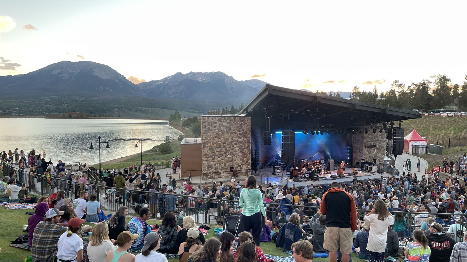 A summer evening concert crowd on the lawn at the Dillon Amphitheater beside Lake Dillon